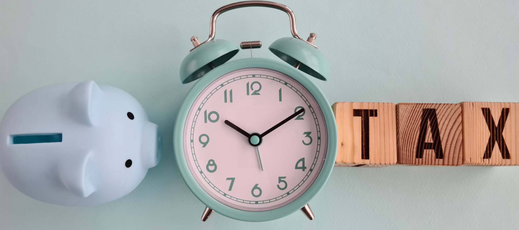 A piggy bank, an alarm clock, and wooden blocks that spell "TAX." Article title: Tax Center [2025]