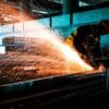 Manufacture worker sanding. Article title: Manufacturing Rebounds Despite Tariff Pressures